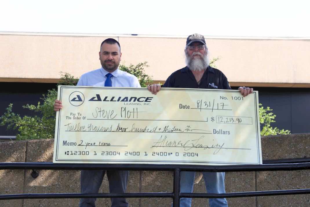 Image of two men holding large check written out to Steve Plott