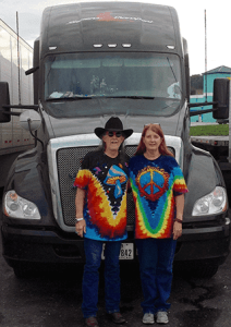 Image of Randy Wales and Elizabeth Cooper wearing matching tie-dye shirts standing in front of black truck