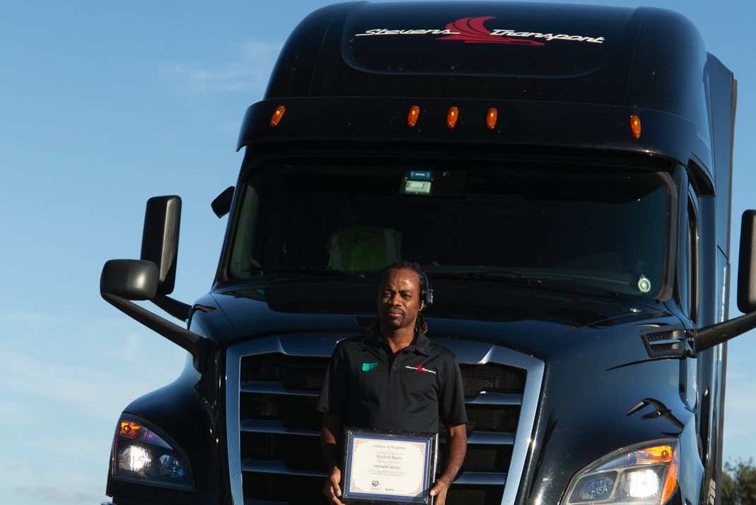 Image of Royford Burris in front of his truck with Angel of the Year Award.