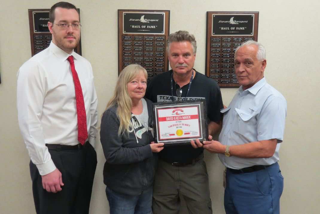 Image of four people, David & Rita Marek in the middle holding team driving award