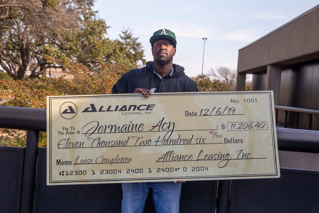 Image of Jermain Acy holding large check