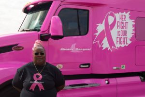 Image of "Pinky" OTR Diva standing in front of her pink, breast cancer awareness truck