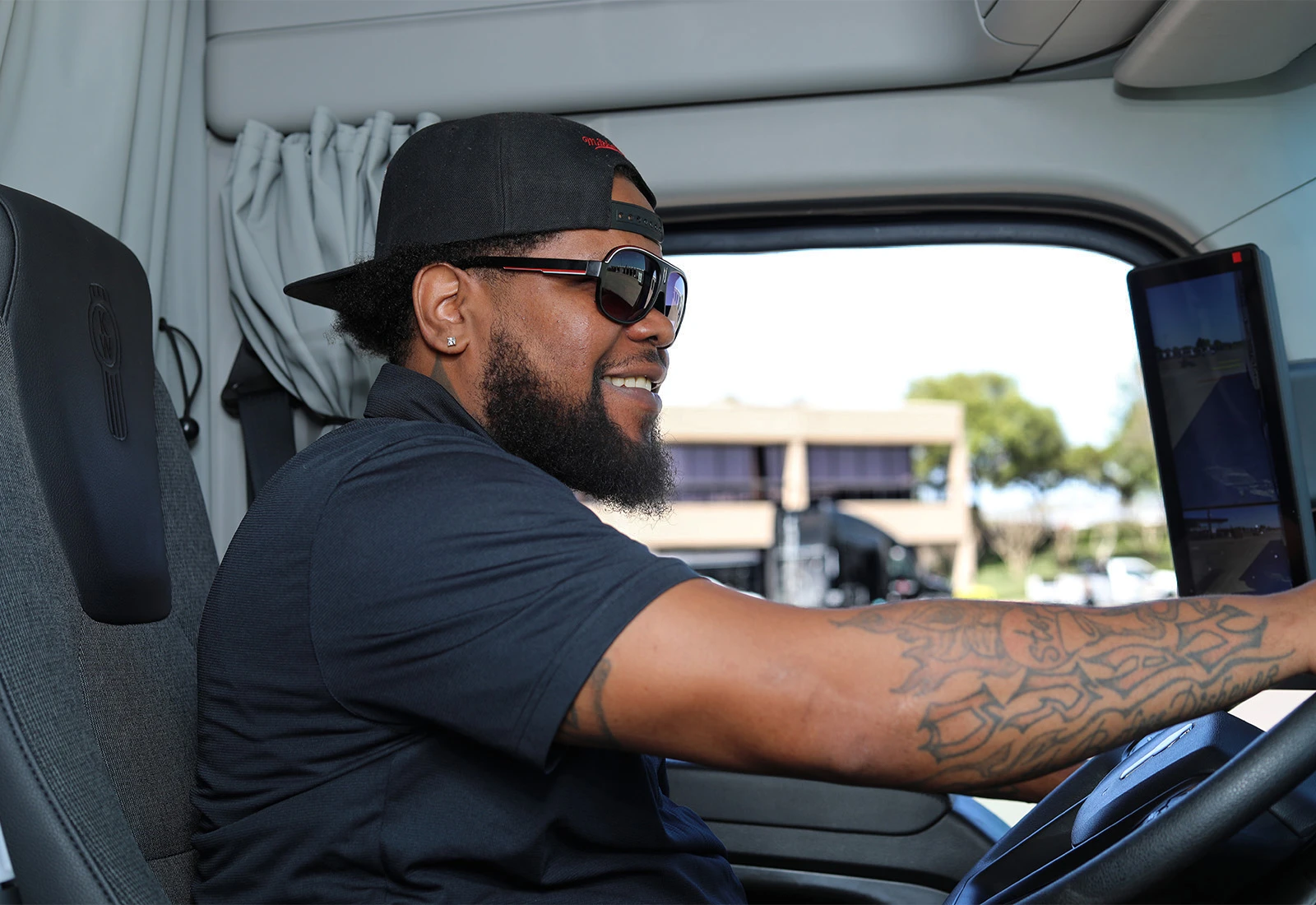 Stevens truck driver holding the steering wheel and looking ahead at the road while smiling