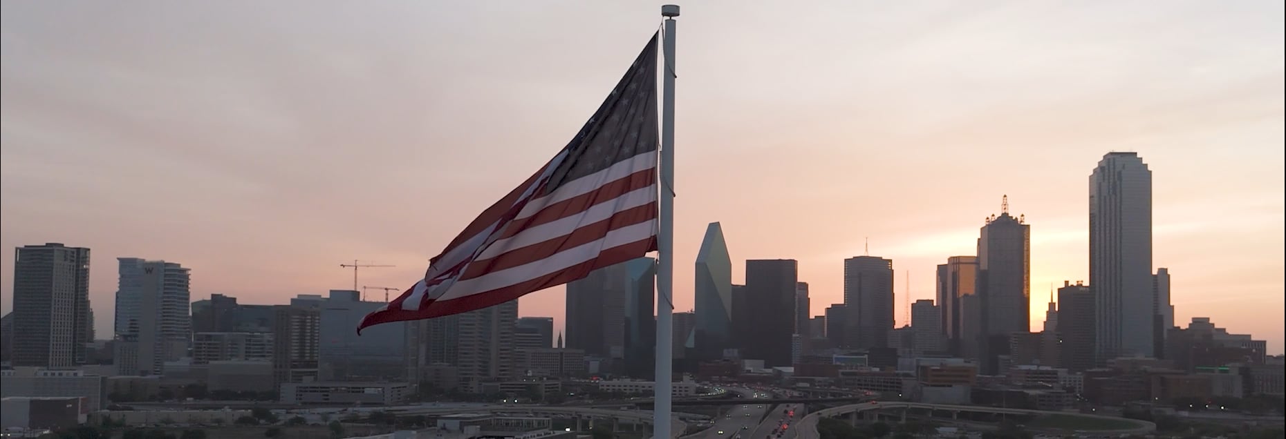 American flag in the wind in front of city skyline and sunset