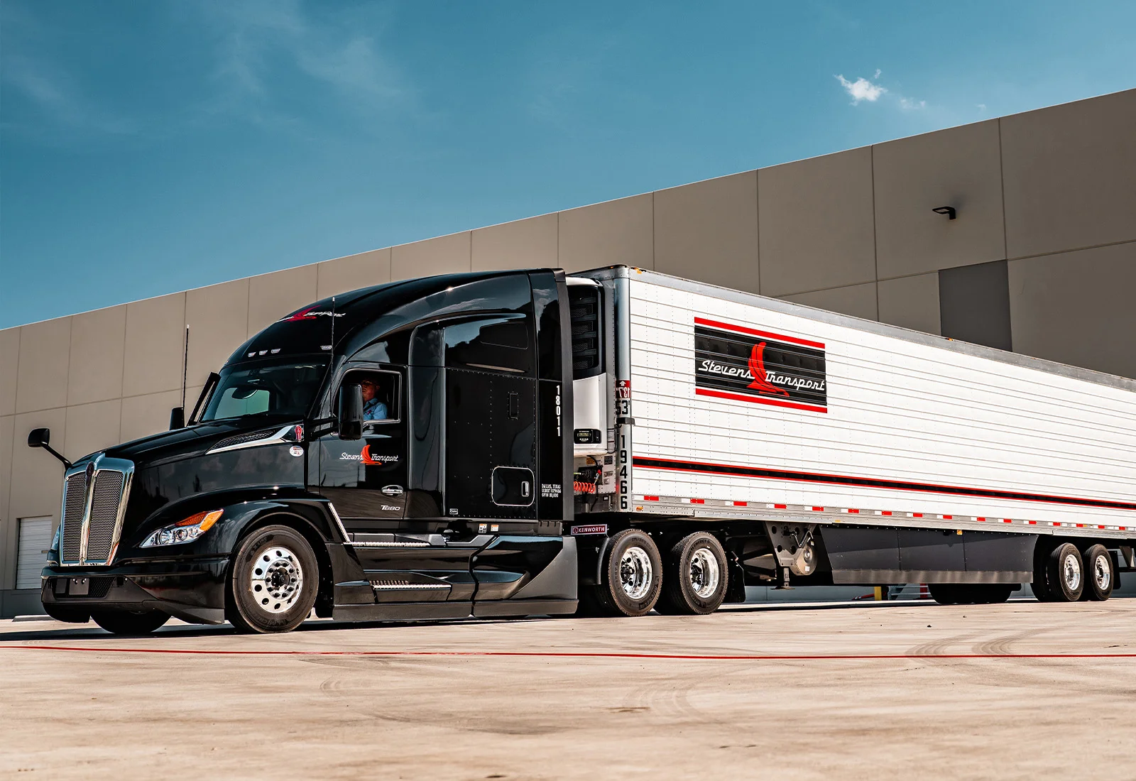 Side view of Stevens Transport semi truck in front of warehouse